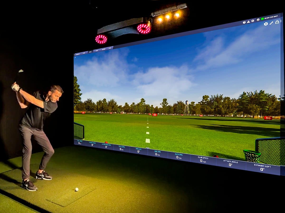 Protee VX golf simulator setup with overhead mounted unit and golfer using full swing in home simulator room