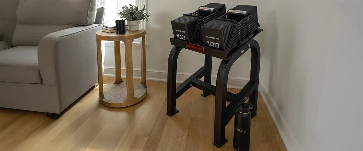 PowerBlock adjustable dumbbells with expandable weight system next to adjustable workout bench