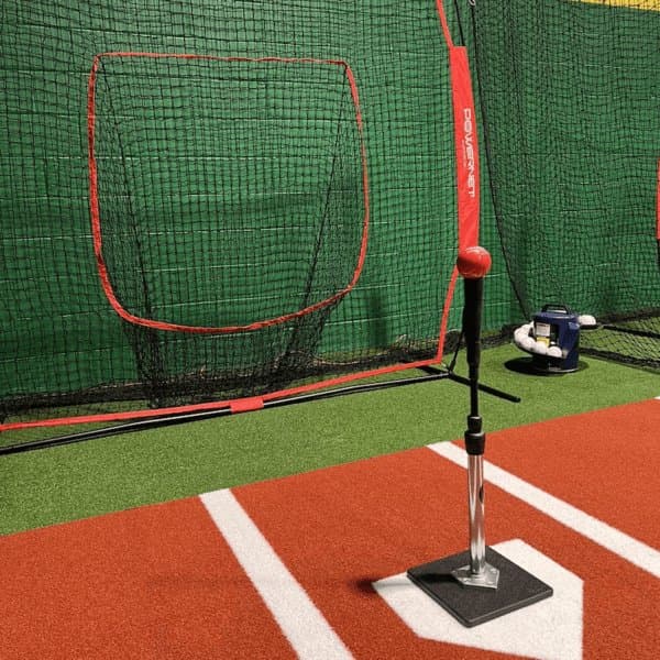 Automated soft-toss machine positioned beside home plate with baseballs queued for batting practice